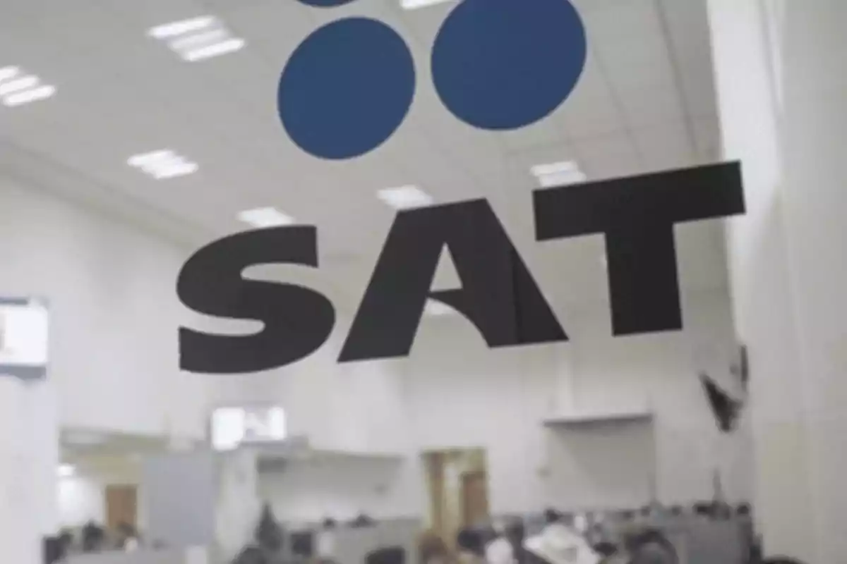 Logotipo del SAT en una oficina con fondo desenfocado.