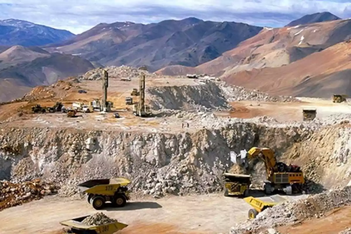 An open-pit mine in a mountainous landscape with heavy machinery working on mineral extraction.