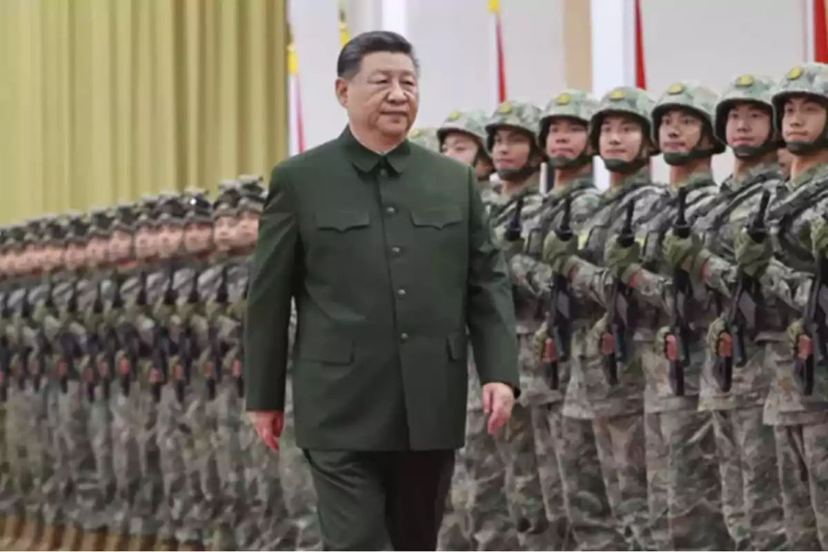 A man in a green uniform walks in front of a row of soldiers in formation.