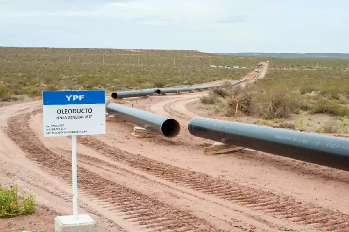 Un oleoducto en construcción en un paisaje árido con un cartel de YPF indicando 