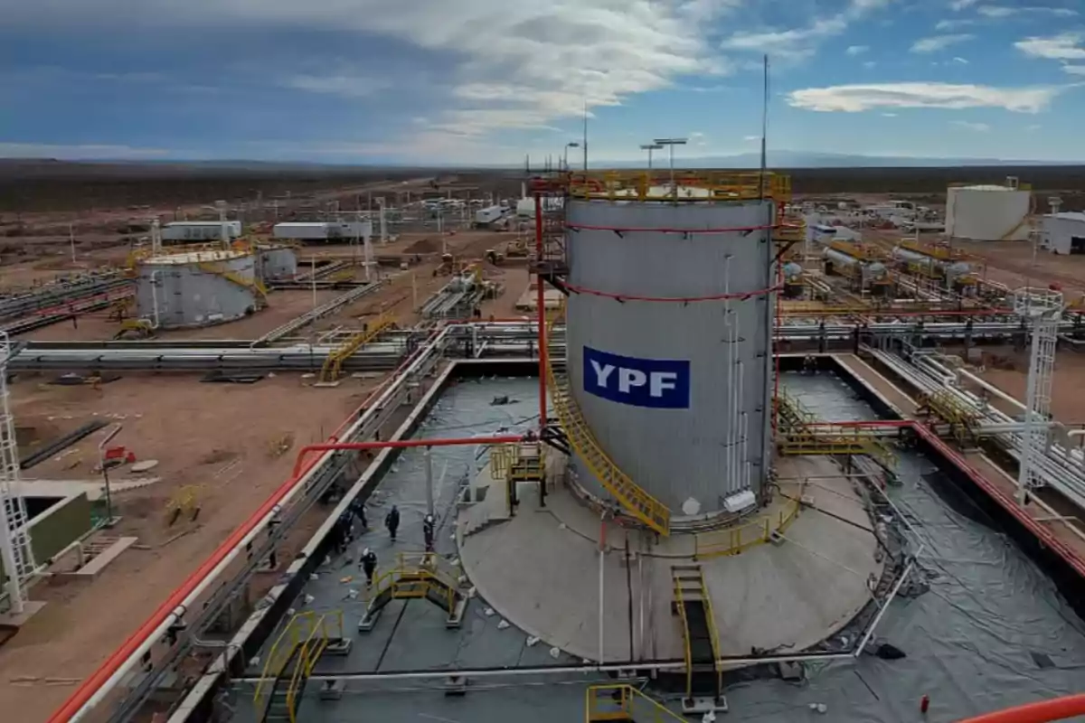 Instalación industrial de YPF en un paisaje desértico con cielo parcialmente nublado.