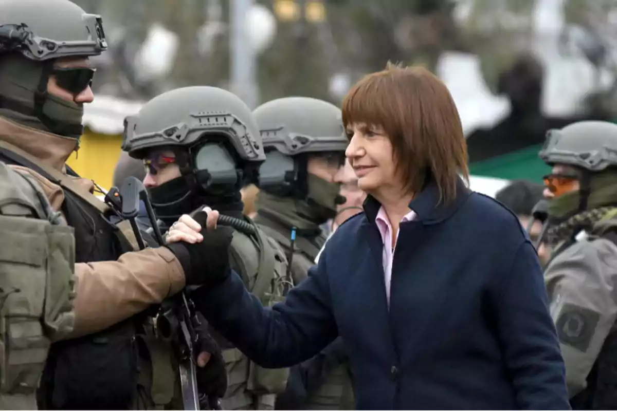 A woman shakes hands with a security forces member wearing tactical gear and a helmet.