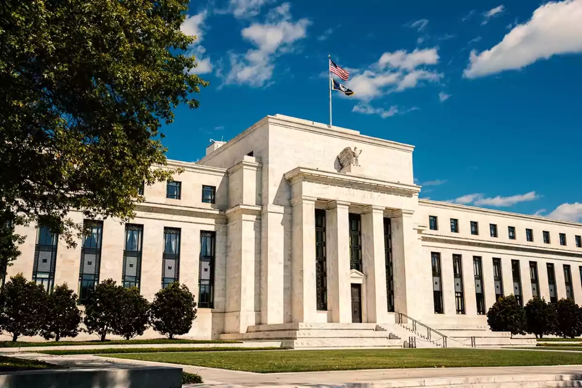 Neoclassical-style government building with columns and a flag waving on top, surrounded by trees and a blue sky. Neoclassical-style government building with columns and a flag waving on top, surrounded by trees and a blue sky.