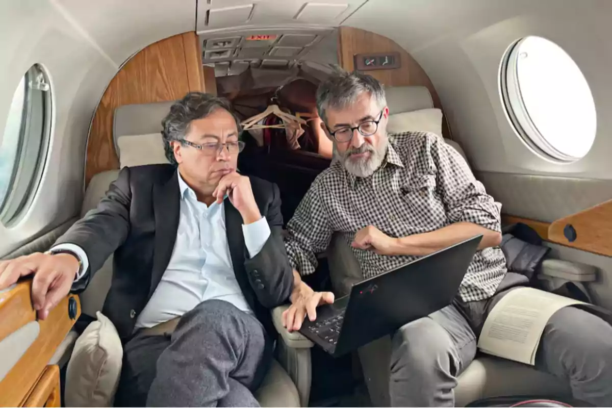 Two people sitting on a private plane intently looking at a laptop. Two people sitting on a private plane intently looking at a laptop.