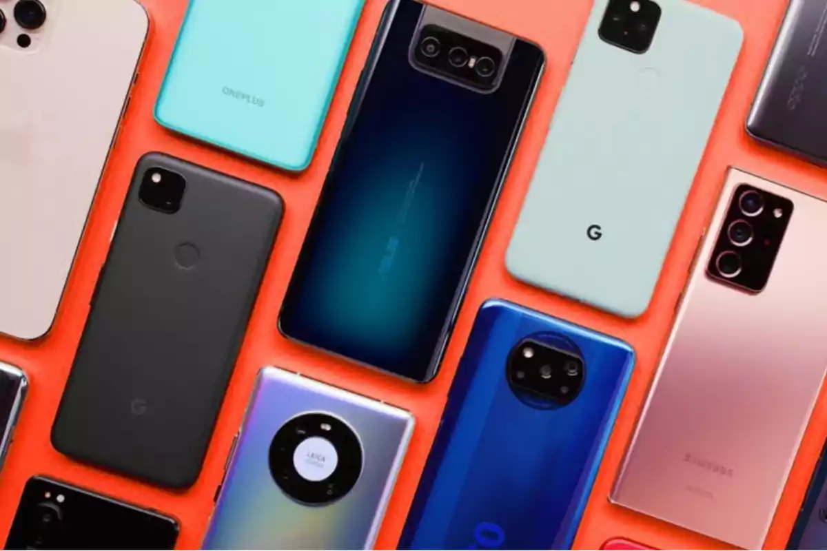 Varios modelos de teléfonos inteligentes de diferentes marcas dispuestos sobre una superficie roja. Varios modelos de teléfonos inteligentes de diferentes marcas dispuestos sobre una superficie roja.