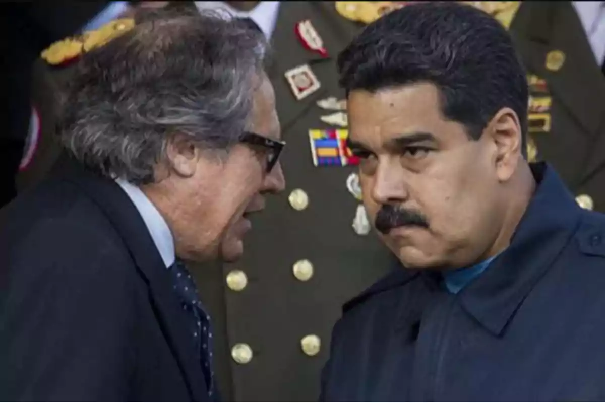 Dos hombres conversan en un evento formal, uno de ellos lleva uniforme militar.