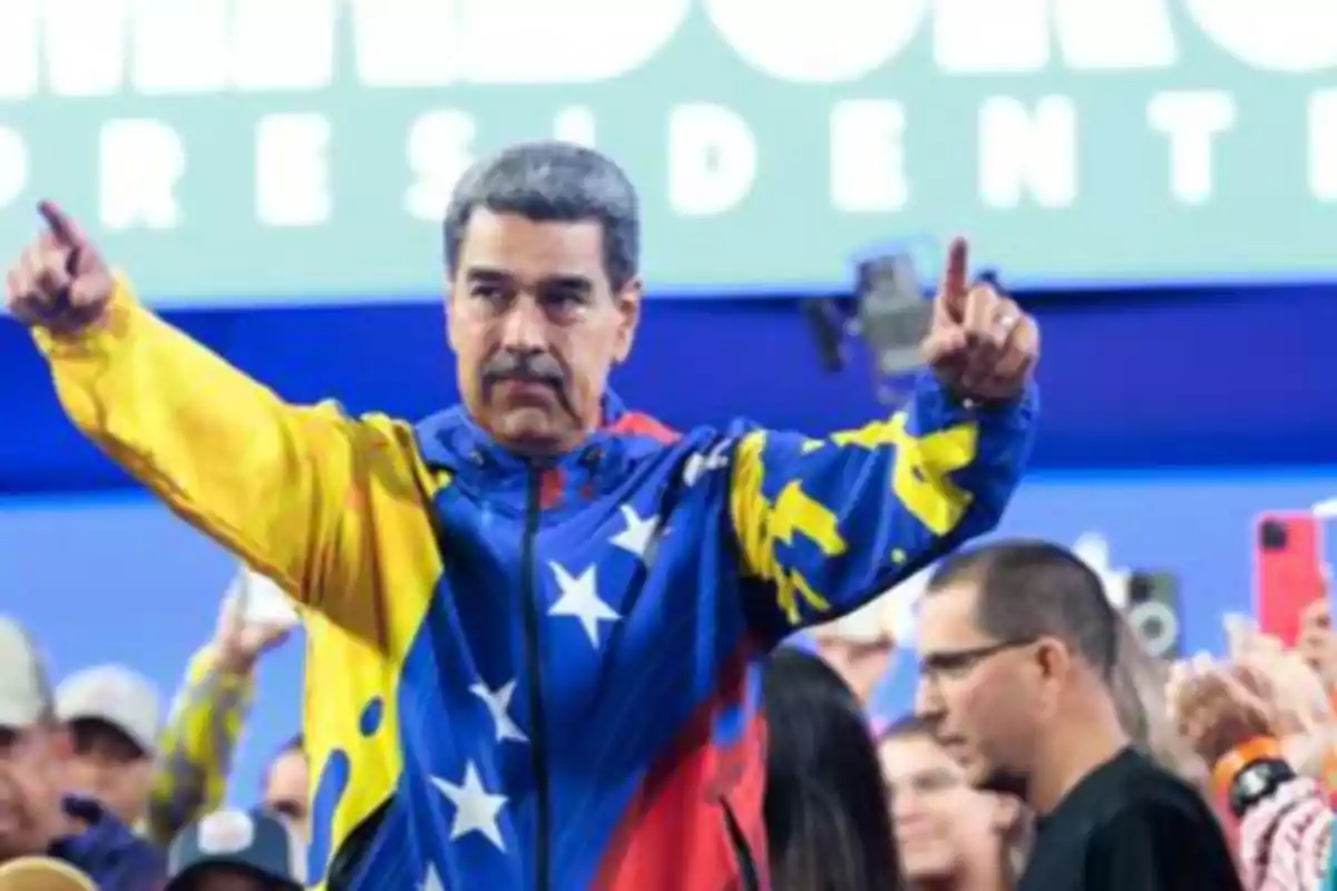 Un hombre con chaqueta de Venezuela levanta los brazos en un evento público. Un hombre con chaqueta de Venezuela levanta los brazos en un evento público.