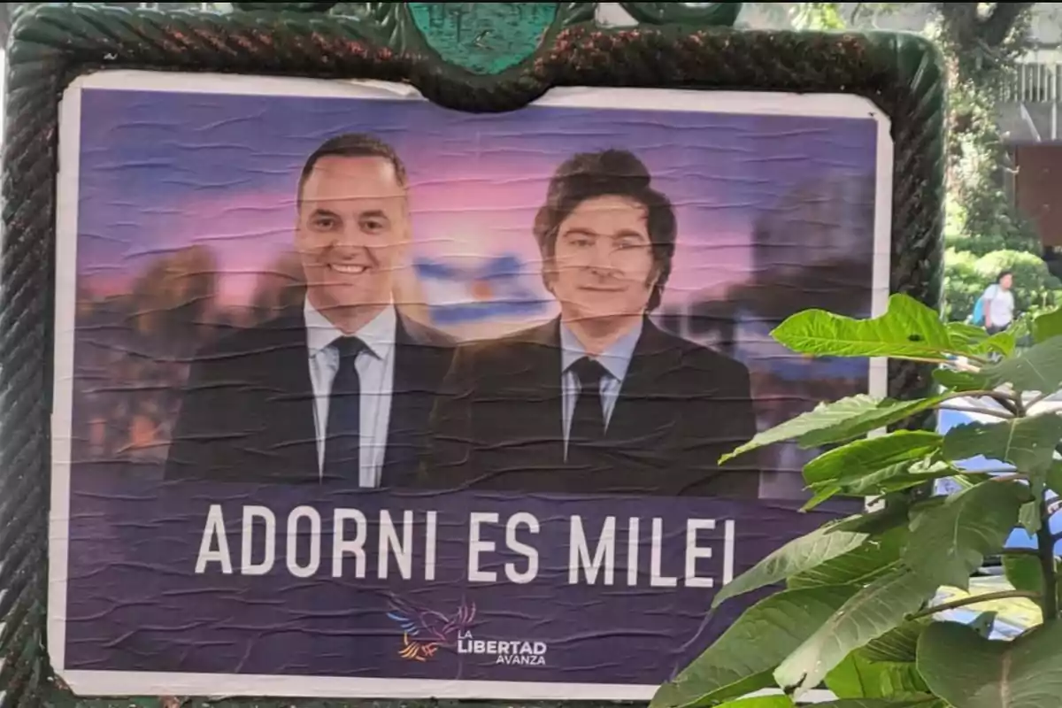 Un cartel político con dos hombres en traje y corbata, con el texto "ADORNI ES MILEI" y el logo de "La Libertad Avanza" en la parte inferior.