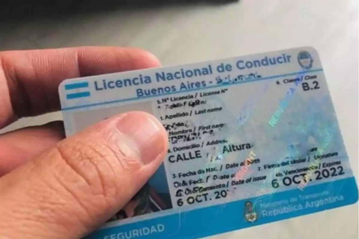 A hand holds an Argentine driver's license, specifically from Buenos Aires, with visible details such as the name, address, and expiration date. A hand holds an Argentine driver's license, specifically from Buenos Aires, with visible details such as the name, address, and expiration date.