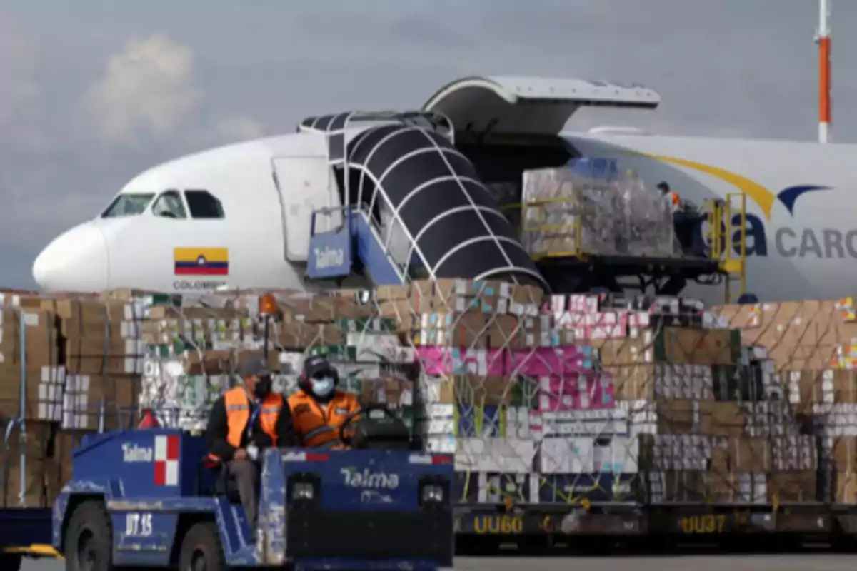 Un avión de carga en un aeropuerto con mercancías siendo transportadas por un vehículo de carga.