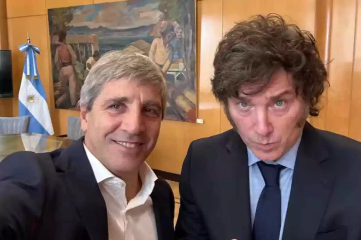 Dos hombres posan para una selfie en una oficina con una bandera argentina y un cuadro en la pared. Dos hombres posan para una selfie en una oficina con una bandera argentina y un cuadro en la pared.