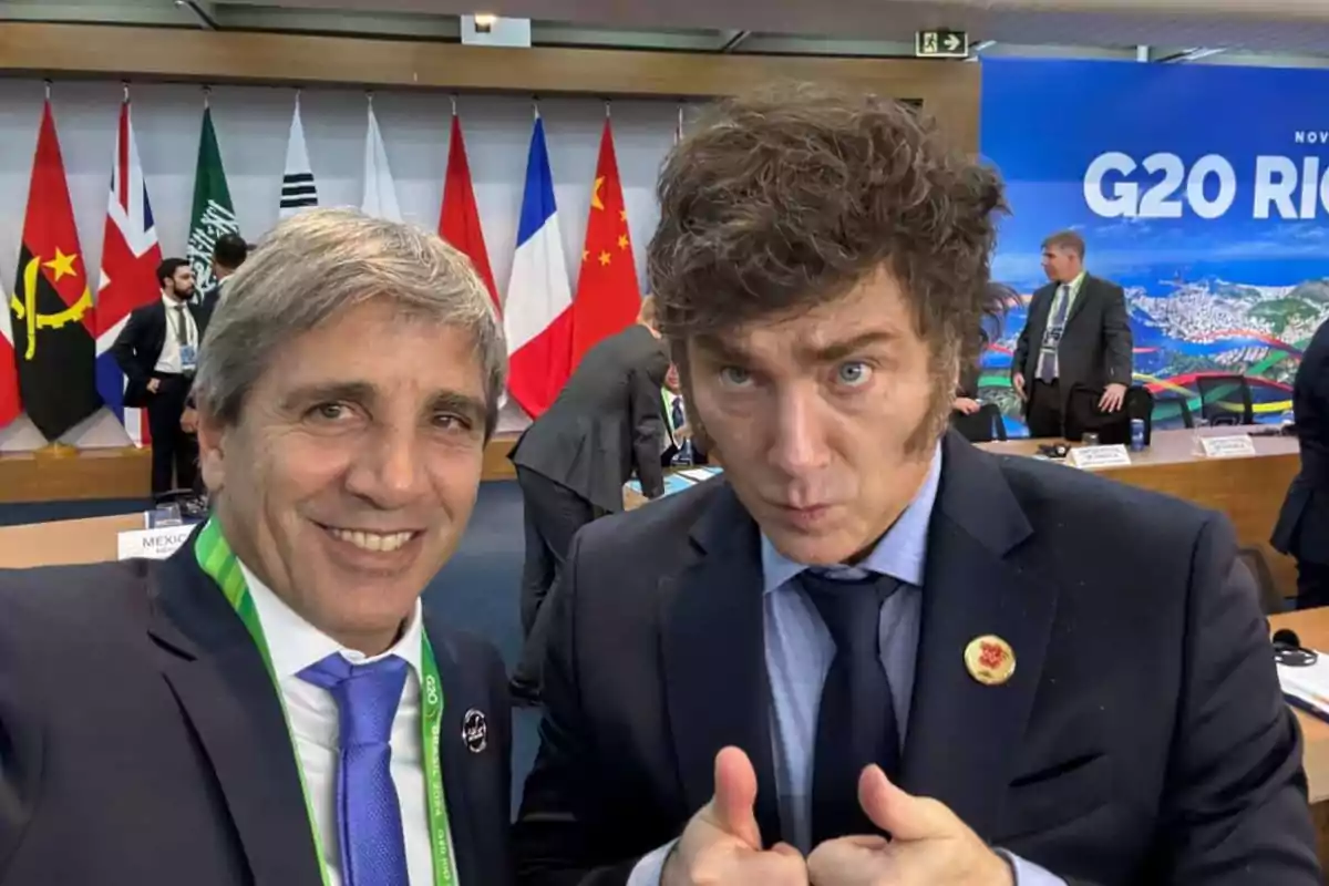 Dos personas posan para una foto en un evento del G20, con varias banderas de fondo y un cartel que dice Dos personas posan para una foto en un evento del G20, con varias banderas de fondo y un cartel que dice