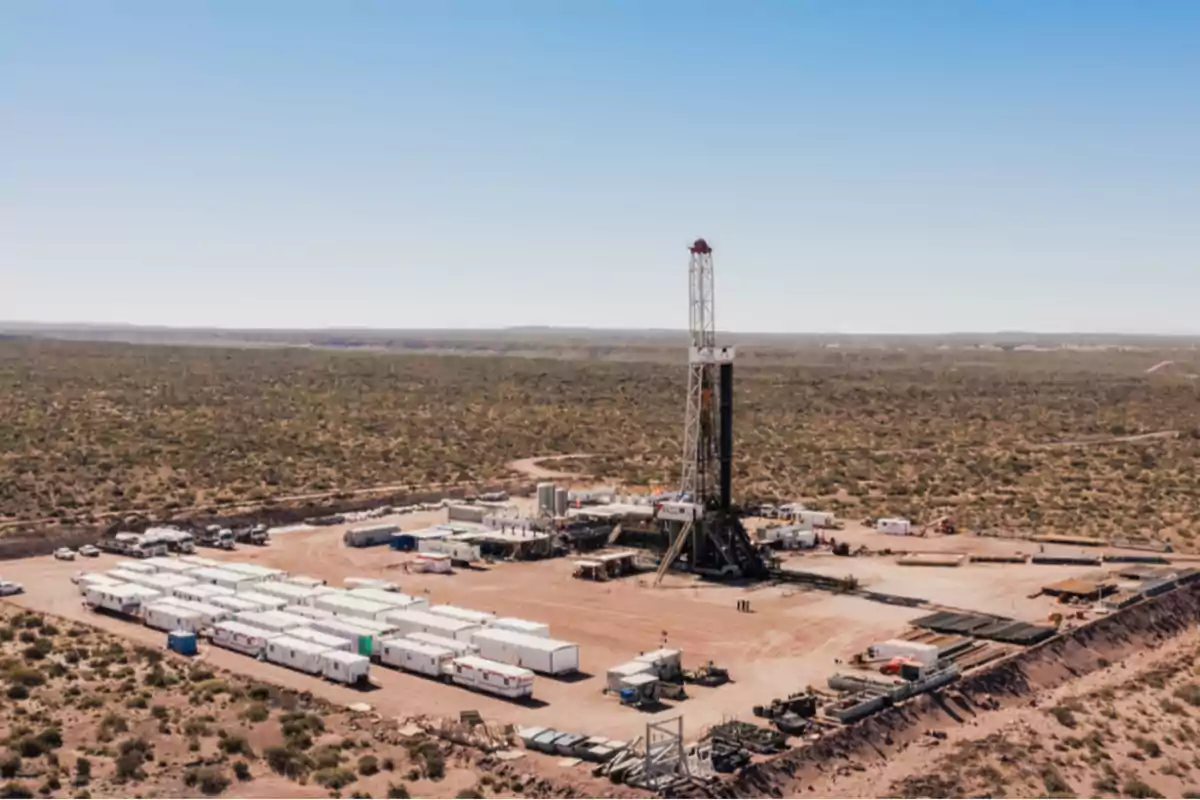 An oil drilling platform in an arid landscape with several structures and vehicles around.