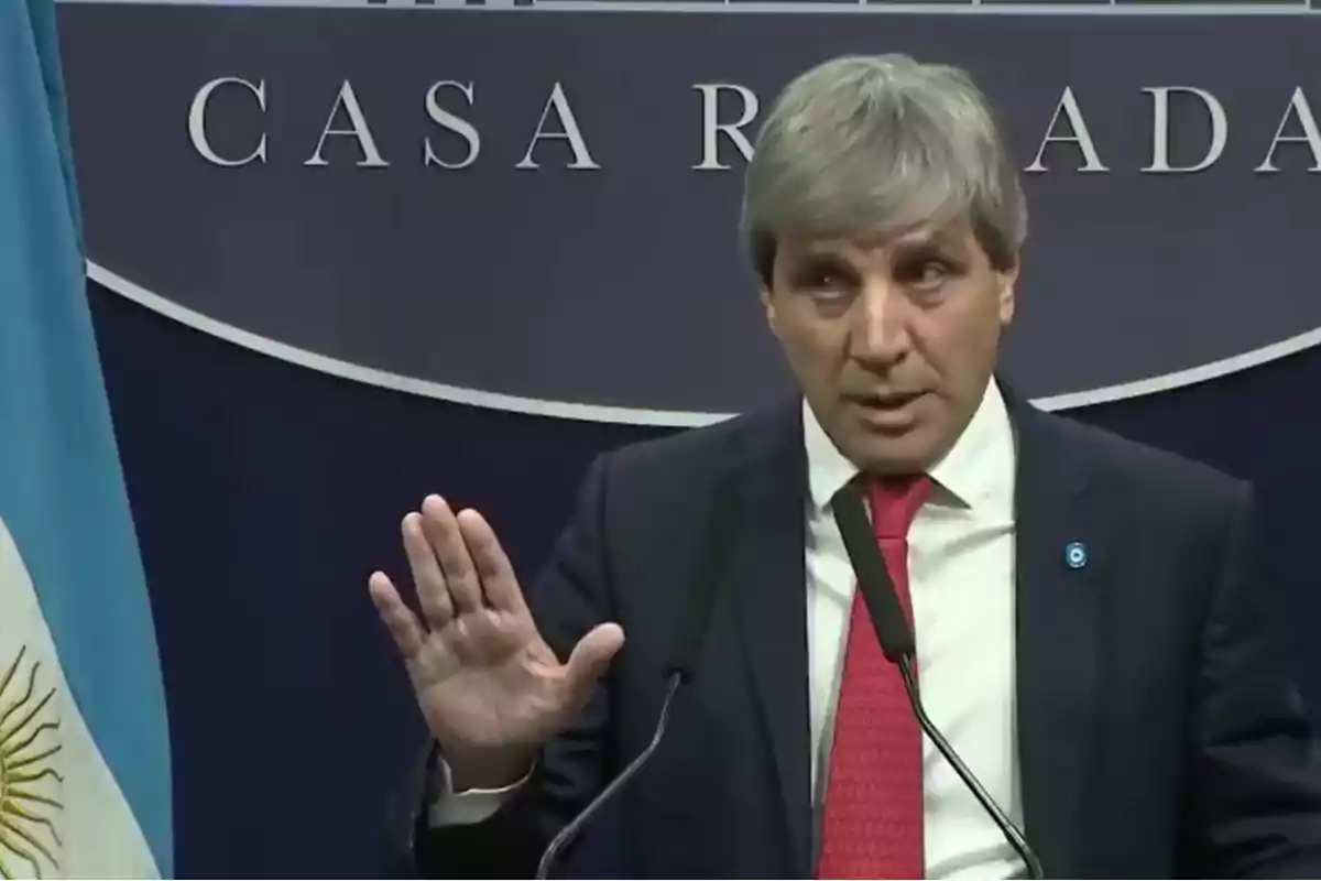 Un hombre de traje y corbata roja habla en un podio con un fondo que dice "Casa Rosada" y una bandera argentina a su lado.