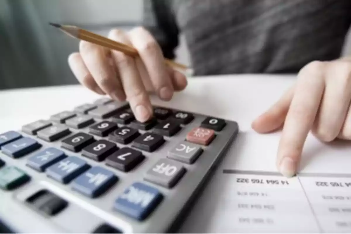 Person using a calculator while reviewing a financial document. Person using a calculator while reviewing a financial document.