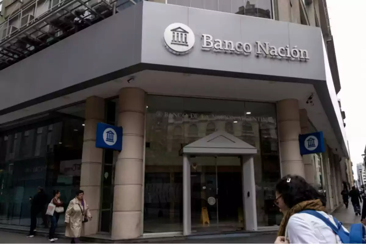 Facade of a Banco Nación branch with people walking on the sidewalk. Facade of a Banco Nación branch with people walking on the sidewalk.
