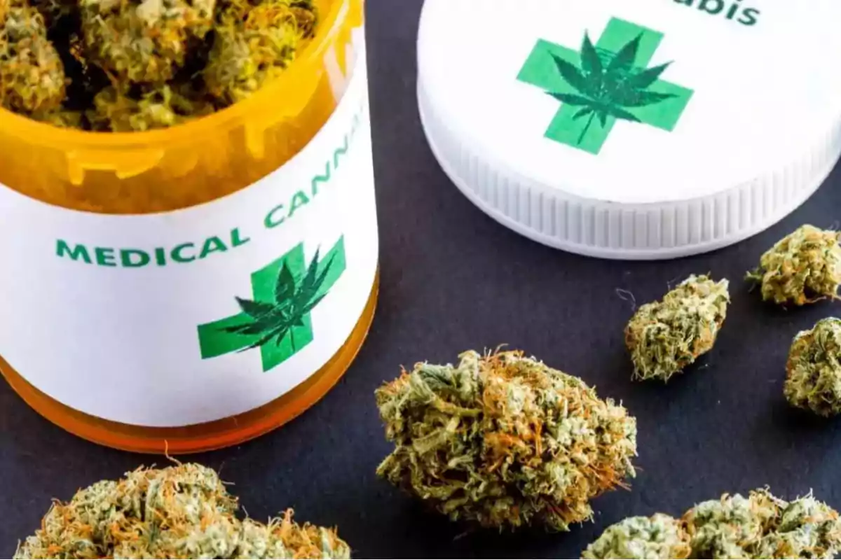 A jar of medical cannabis with marijuana buds around it on a dark surface. A jar of medical cannabis with marijuana buds around it on a dark surface.
