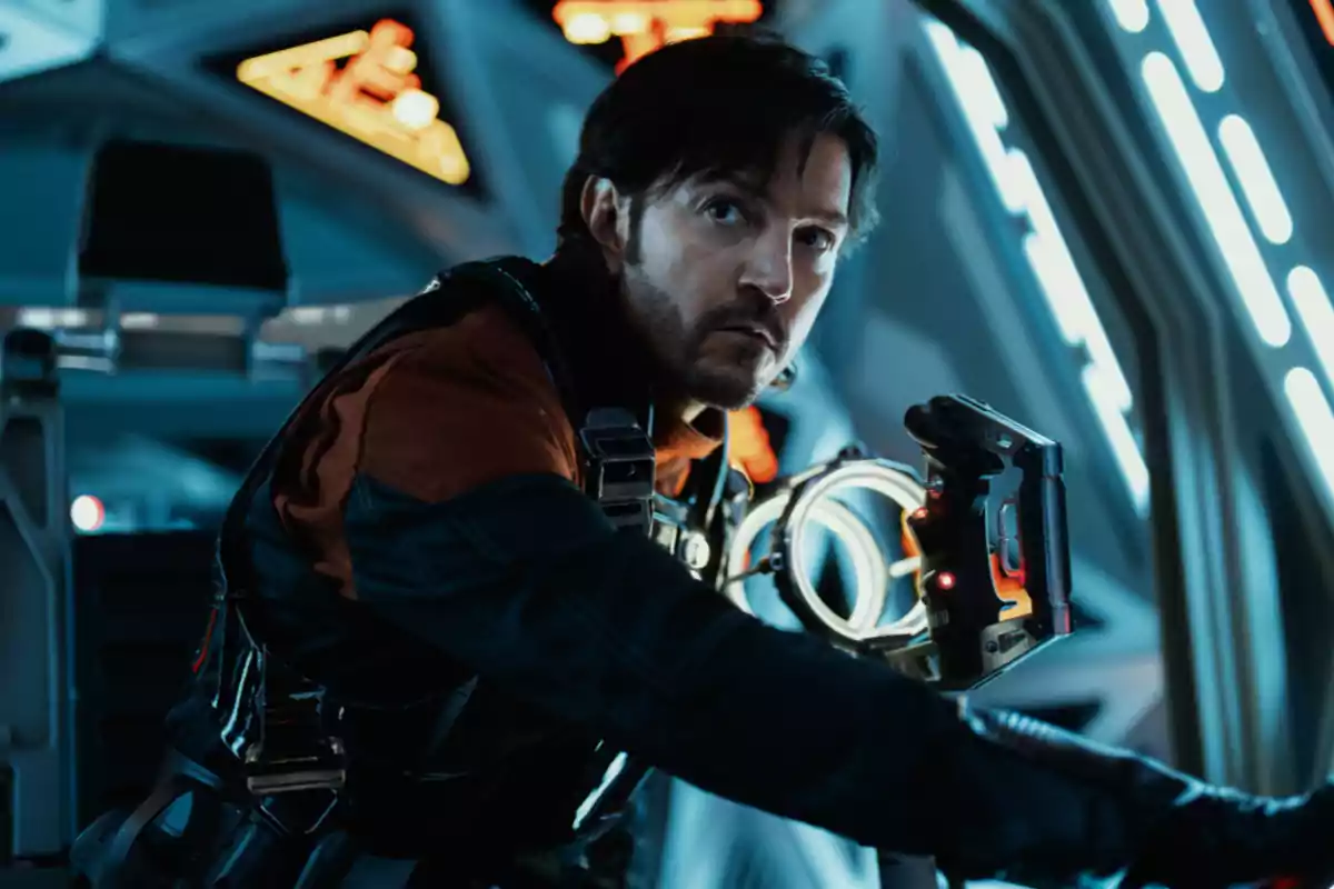 Man with a serious expression wearing a spacesuit inside a futuristic spacecraft illuminated with blue and orange lights Man with a serious expression wearing a spacesuit inside a futuristic spacecraft illuminated with blue and orange lights