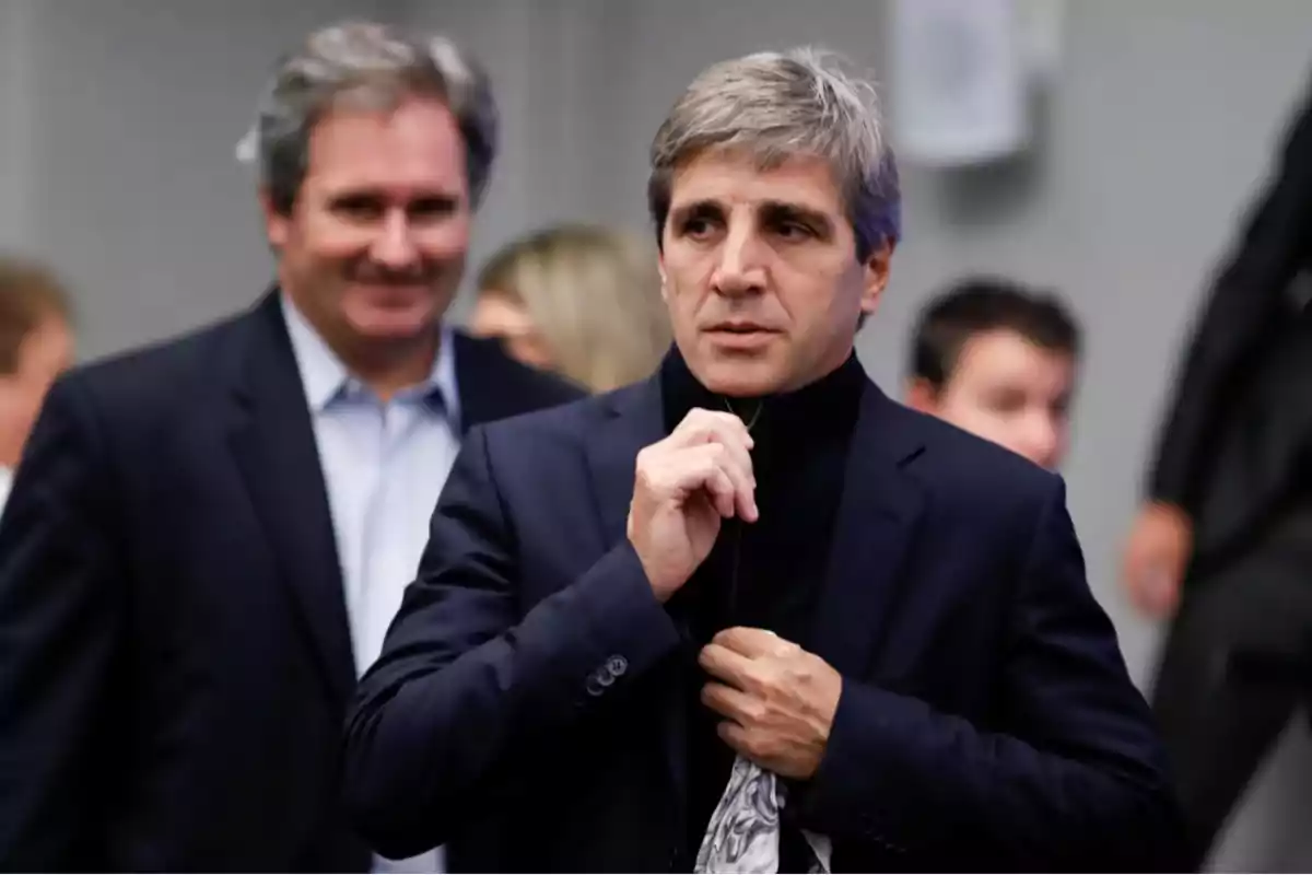 Gray-haired man in a blue blazer zipping up his sweater while another person smiles in the background Gray-haired man in a blue blazer zipping up his sweater while another person smiles in the background