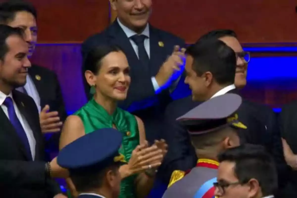 Personas vestidas de manera formal aplauden y sonríen en un evento oficial