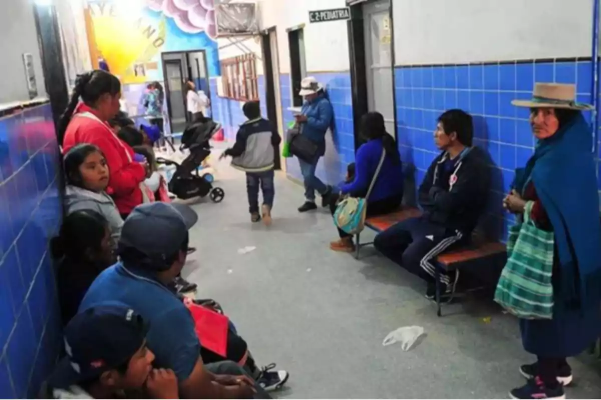 People waiting in the lobby of a health center with blue walls and a colorful mural in the background People waiting in the lobby of a health center with blue walls and a colorful mural in the background