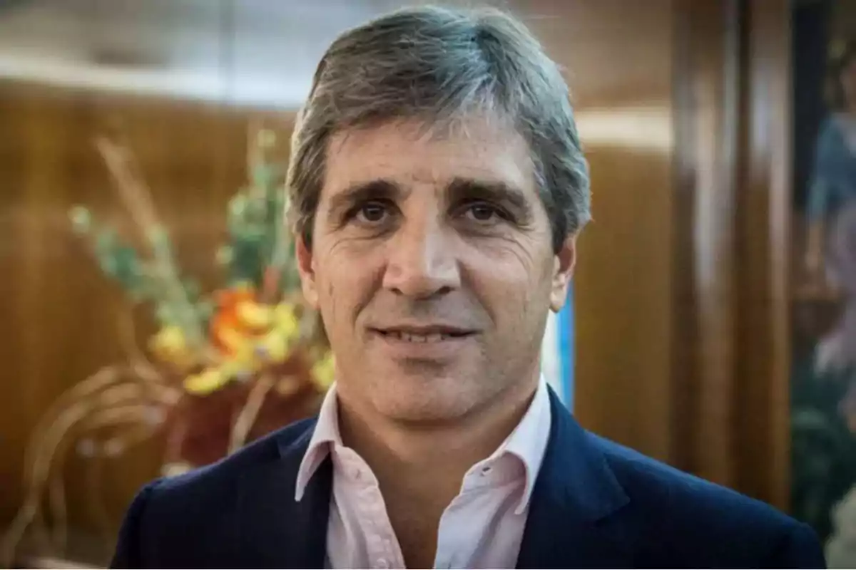 Hombre de cabello canoso y corto vistiendo saco azul y camisa clara con fondo desenfocado y flores detrás Hombre de cabello canoso y corto vistiendo saco azul y camisa clara con fondo desenfocado y flores detrás