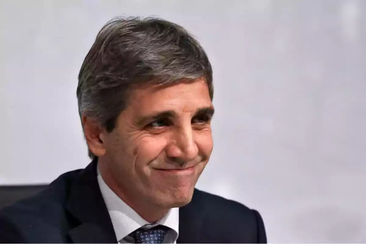 Hombre de cabello canoso y traje oscuro sonriendo frente a un fondo claro Hombre de cabello canoso y traje oscuro sonriendo frente a un fondo claro