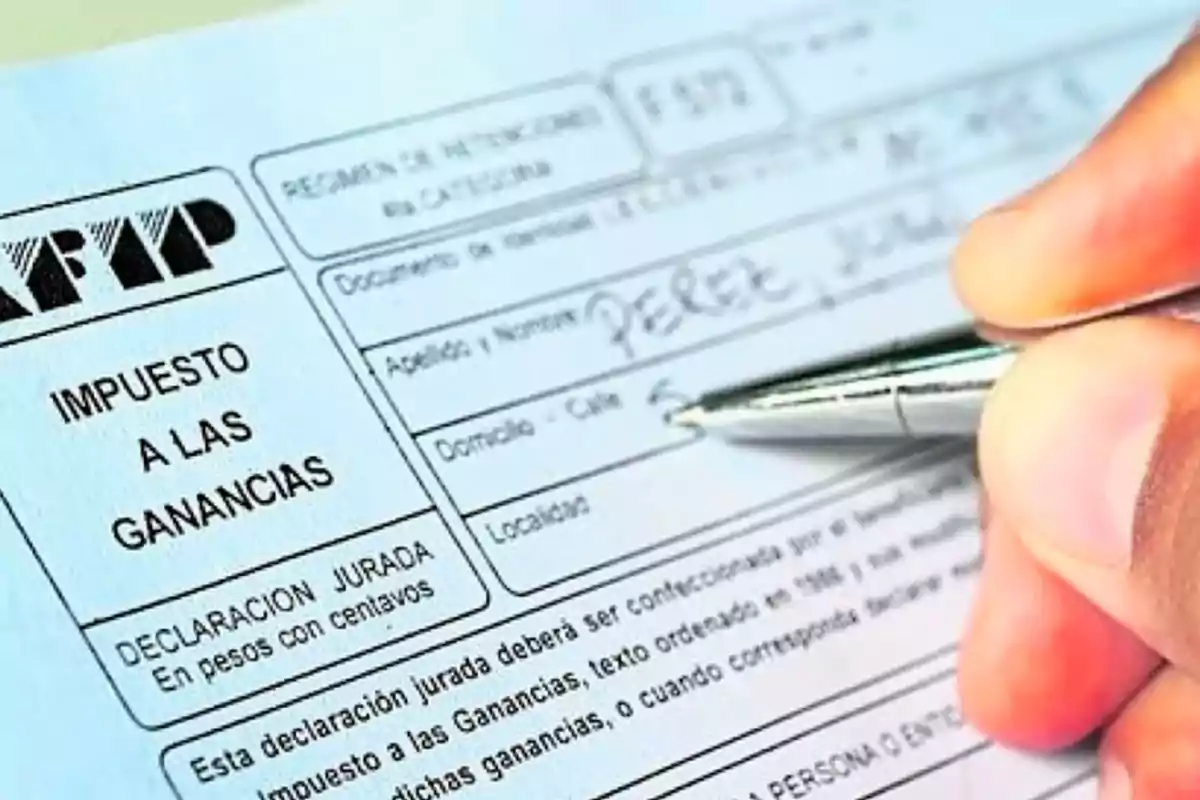 Persona completando un formulario de impuesto a las ganancias de la AFIP con un bolígrafo Persona completando un formulario de impuesto a las ganancias de la AFIP con un bolígrafo