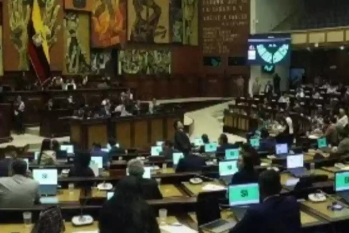 Parliamentary session in the plenary of the National Assembly of Ecuador with legislators seated in front of computers and screens displaying voting results Parliamentary session in the plenary of the National Assembly of Ecuador with legislators seated in front of computers and screens displaying voting results