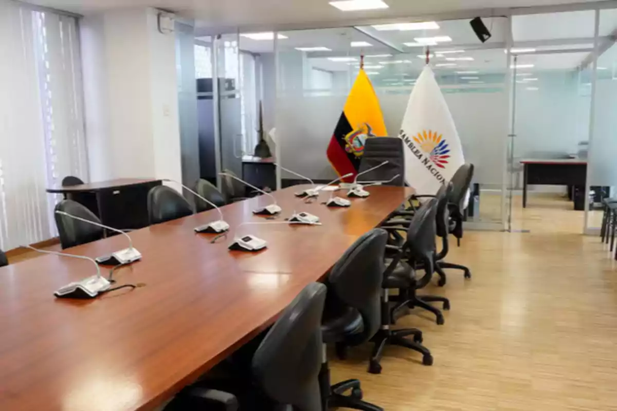 Meeting room with a wooden table, several black chairs, microphones, and in the background the flags of Ecuador and the National Assembly Meeting room with a wooden table, several black chairs, microphones, and in the background the flags of Ecuador and the National Assembly