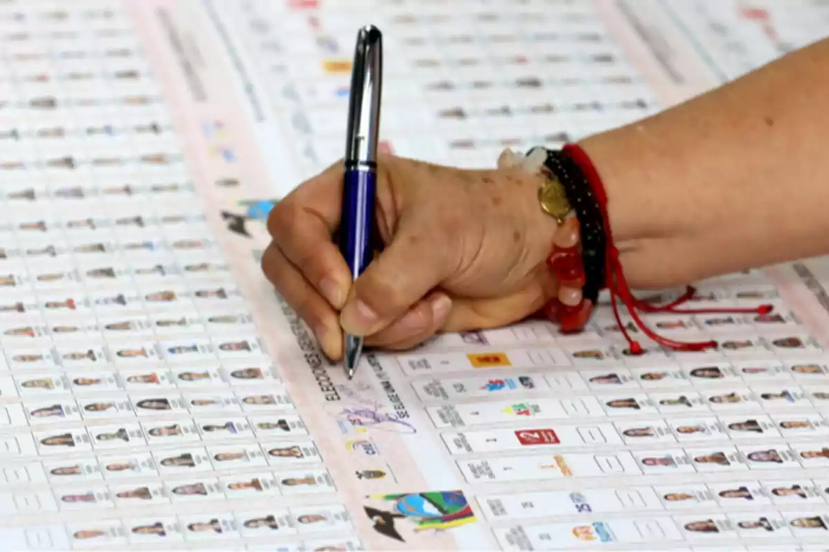 Persona marcando una boleta electoral con un bolígrafo sobre una mesa