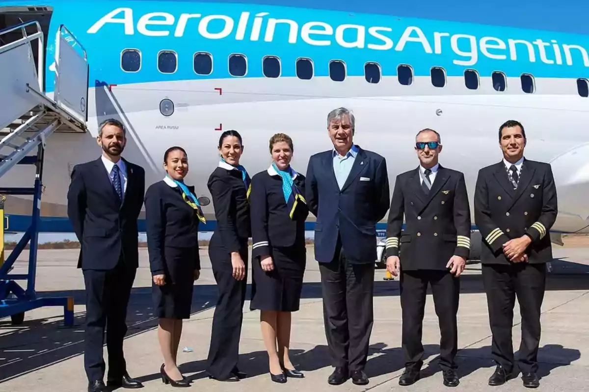 Personal de Aerolíneas Argentinas posando frente a un avión en la pista de un aeropuerto Personal de Aerolíneas Argentinas posando frente a un avión en la pista de un aeropuerto