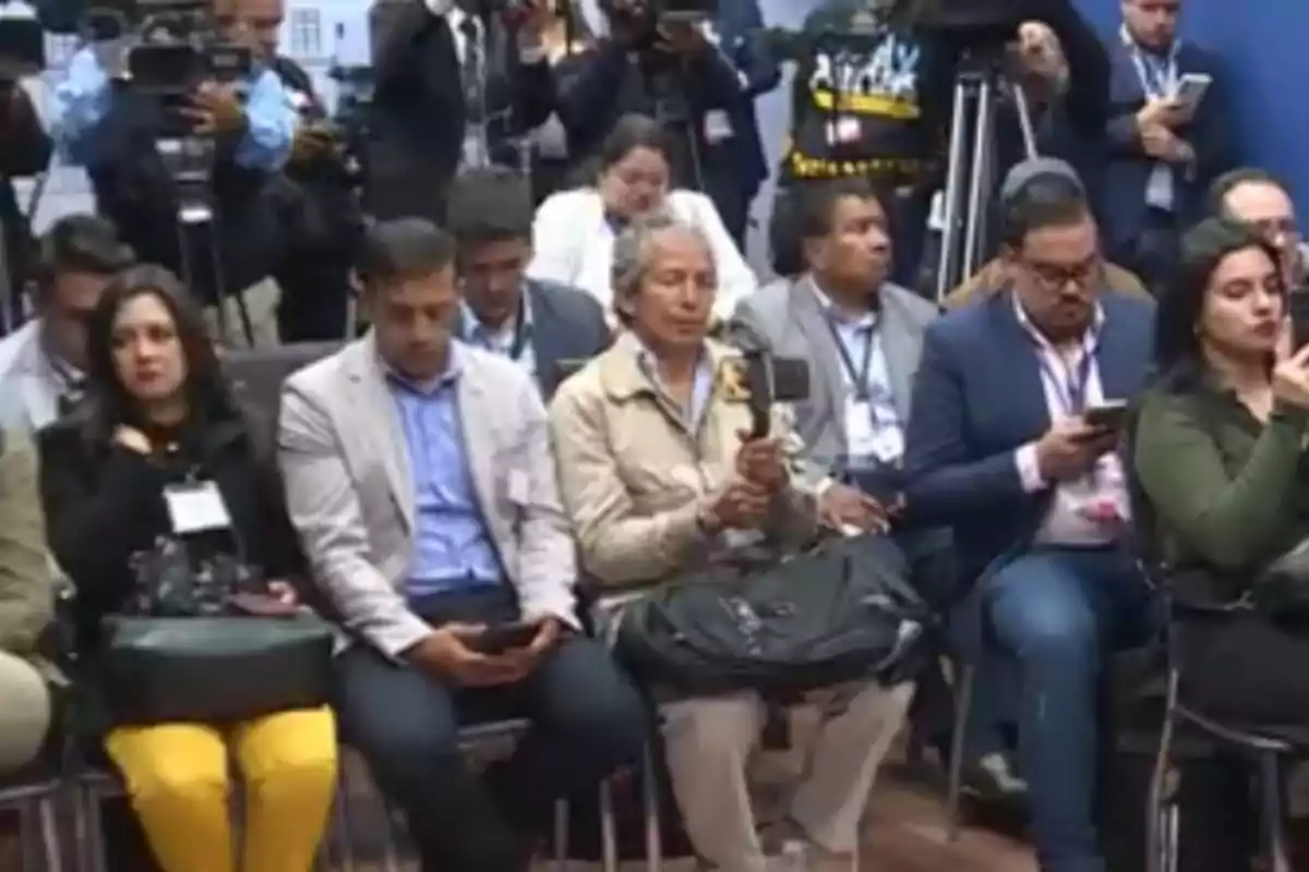 Personas sentadas en una conferencia de prensa con cámaras y teléfonos móviles Personas sentadas en una conferencia de prensa con cámaras y teléfonos móviles