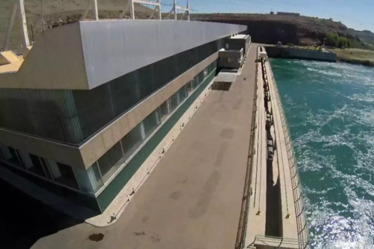 Edificio industrial junto a un canal de agua con barandales y cielo despejado Edificio industrial junto a un canal de agua con barandales y cielo despejado