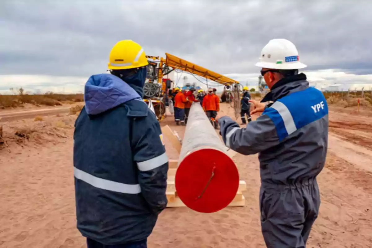 Workers wearing helmets and safety clothing supervise the installation of a gas pipeline in a rural area. Workers wearing helmets and safety clothing supervise the installation of a gas pipeline in a rural area.