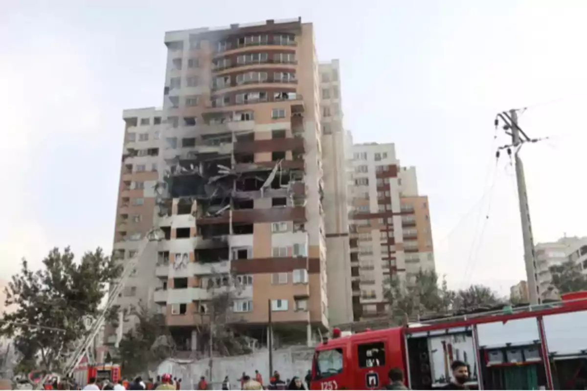 Apartment building with severe damage on several floors while firefighters work at the scene with a ladder and a fire truck Apartment building with severe damage on several floors while firefighters work at the scene with a ladder and a fire truck