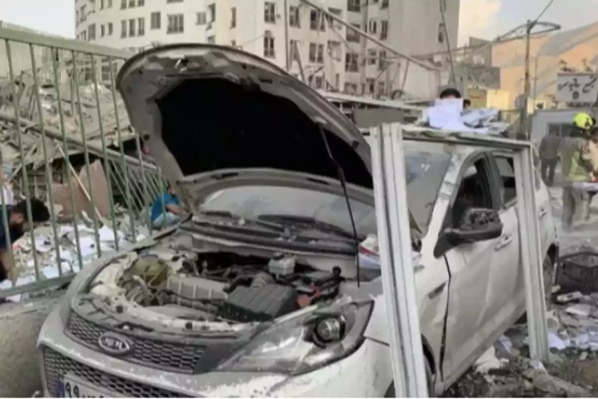 White car damaged with the hood open and debris around it in an urban area affected by a disaster White car damaged with the hood open and debris around it in an urban area affected by a disaster