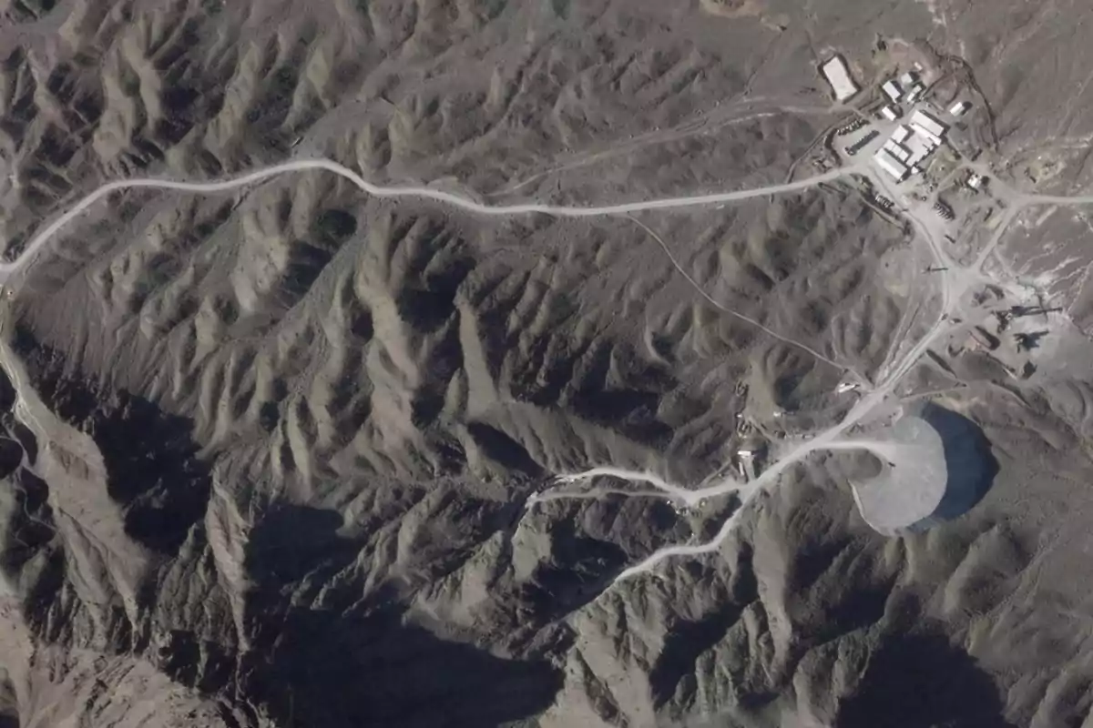 Aerial view of a mountainous terrain with winding roads and several buildings in the upper right corner Aerial view of a mountainous terrain with winding roads and several buildings in the upper right corner
