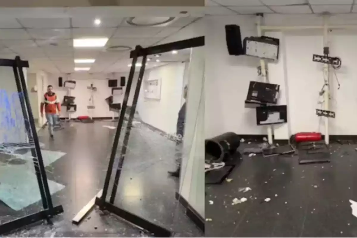 Office with broken glass doors, destroyed screens, and objects scattered on the floor, showing an environment of vandalism and disorder Office with broken glass doors, destroyed screens, and objects scattered on the floor, showing an environment of vandalism and disorder