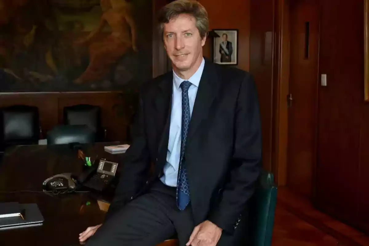 Hombre de traje sentado en el borde de un escritorio en una oficina elegante Hombre de traje sentado en el borde de un escritorio en una oficina elegante