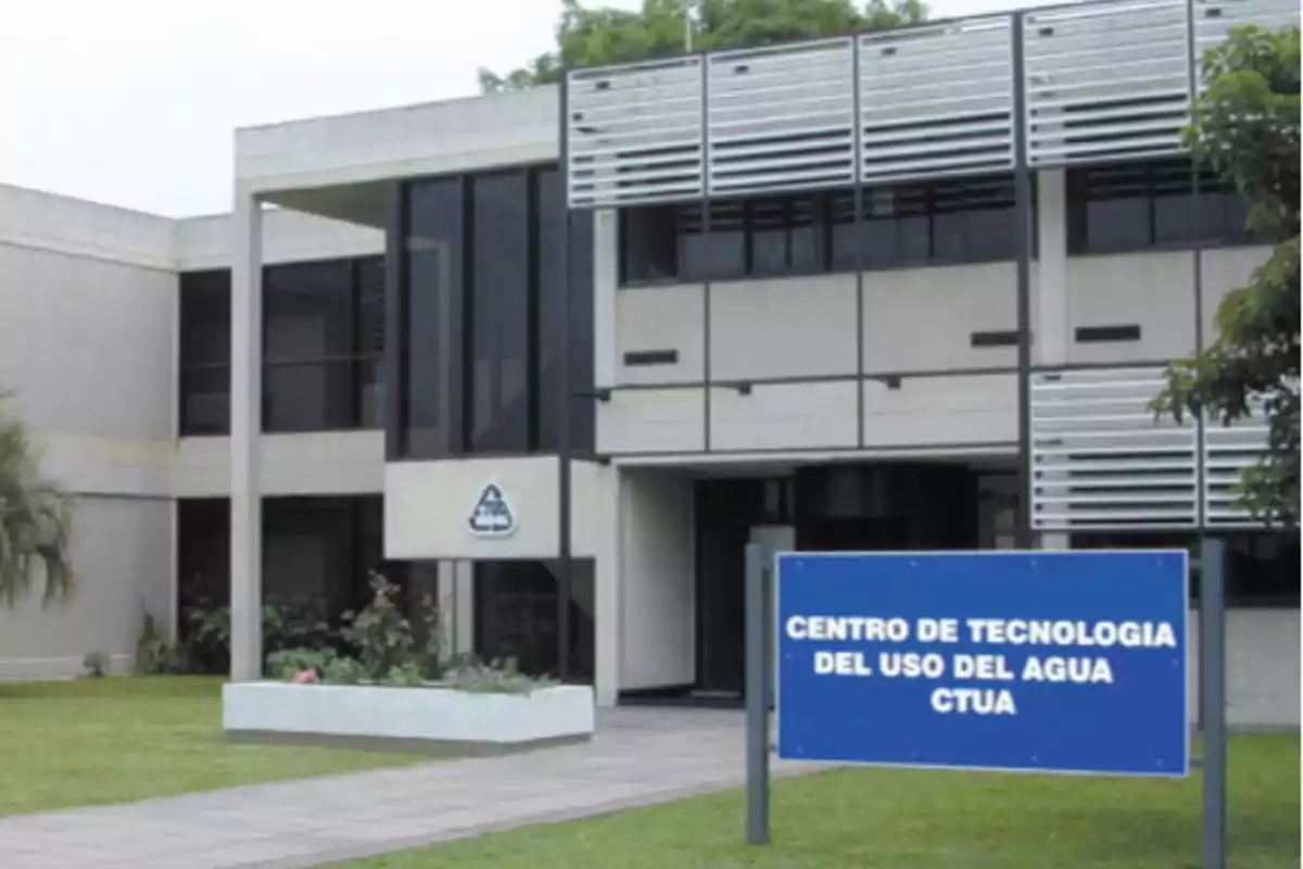 Edificio moderno con ventanales y un letrero azul al frente que dice Centro de Tecnología del Uso del Agua CTUA Edificio moderno con ventanales y un letrero azul al frente que dice Centro de Tecnología del Uso del Agua CTUA