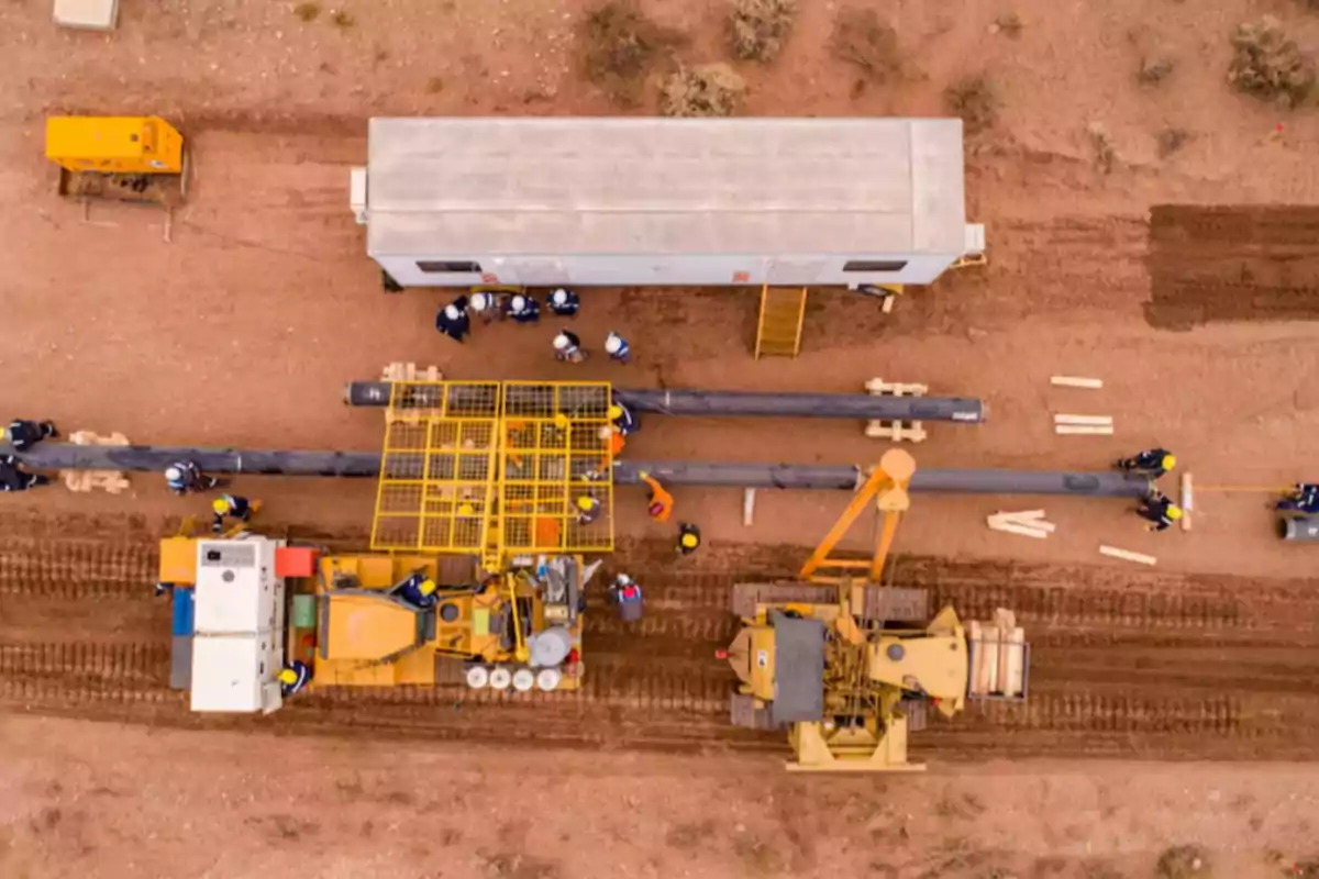 Vista aérea de una obra de construcción donde trabajadores y maquinaria pesada están instalando tuberías en un terreno de tierra Vista aérea de una obra de construcción donde trabajadores y maquinaria pesada están instalando tuberías en un terreno de tierra