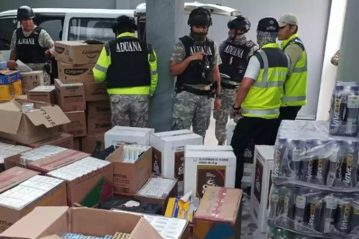 Several customs agents and military personnel inspect boxes and seized goods during an operation.