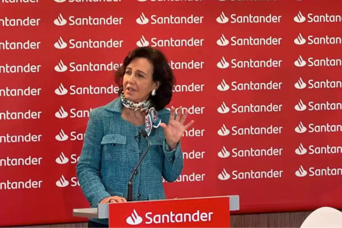 Mujer hablando en un podio con el logotipo de Santander de fondo.