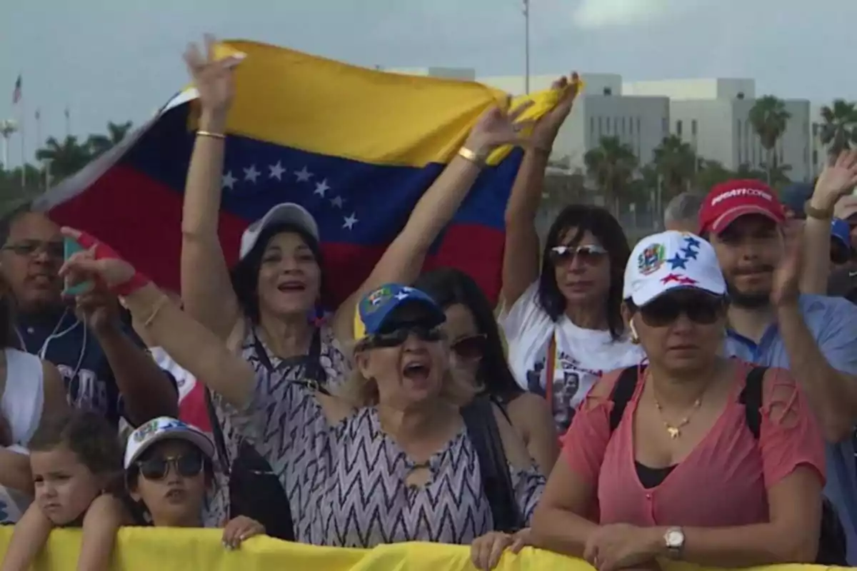 Un grupo de personas celebra mientras sostiene una bandera de Venezuela.