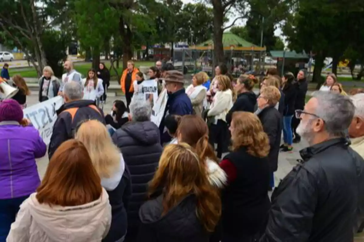 A group of people gathered outdoors participating in a peaceful demonstration in a tree-lined plaza. A group of people gathered outdoors participating in a peaceful demonstration in a tree-lined plaza.