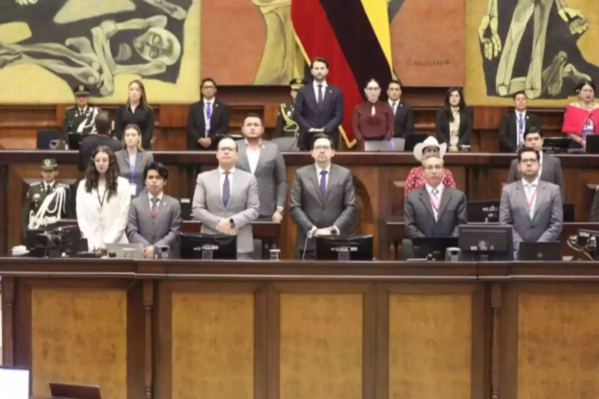 People standing inside a parliamentary chamber with murals and a flag in the background People standing inside a parliamentary chamber with murals and a flag in the background
