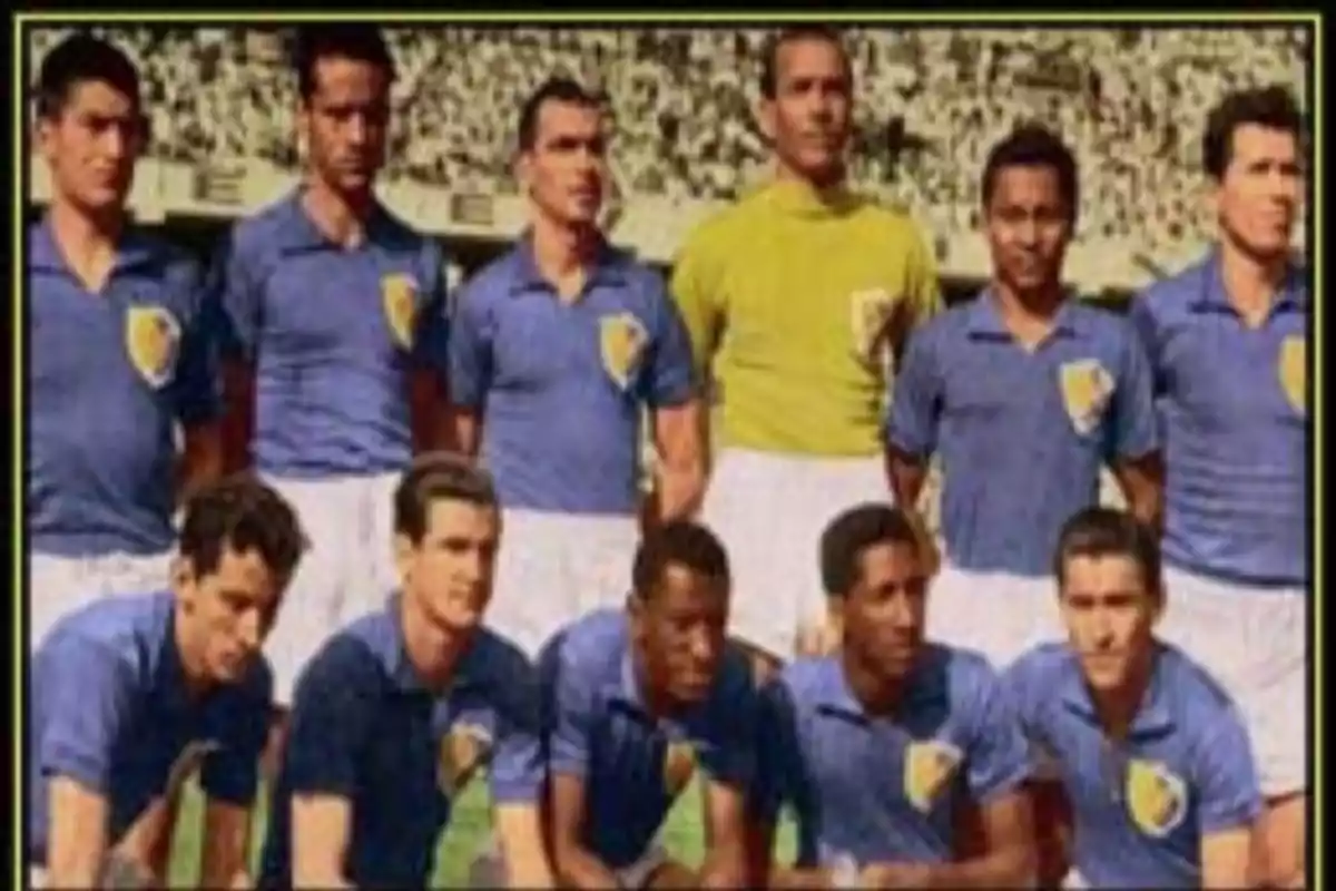 Un equipo de fútbol posando para una foto grupal en un estadio, con jugadores vistiendo camisetas azules y pantalones blancos. Un equipo de fútbol posando para una foto grupal en un estadio, con jugadores vistiendo camisetas azules y pantalones blancos.