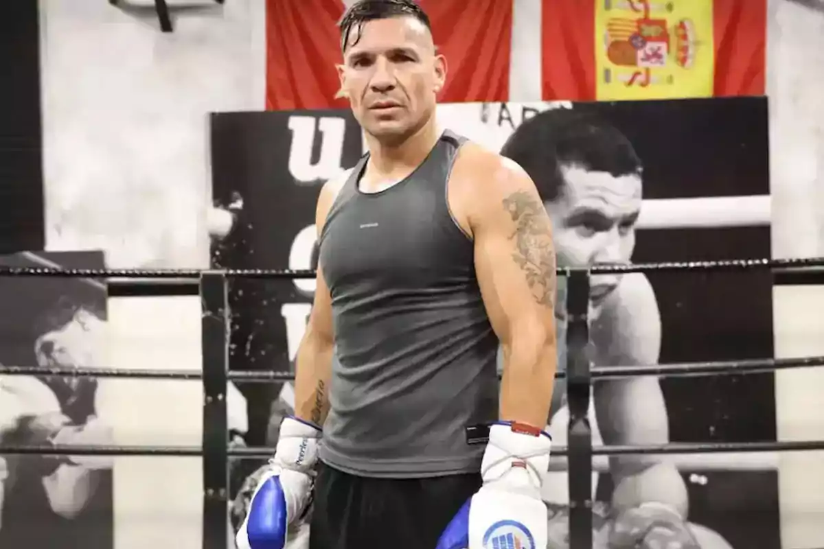 Boxeador con guantes y camiseta sin mangas posando en un ring de boxeo con una bandera de España al fondo Boxeador con guantes y camiseta sin mangas posando en un ring de boxeo con una bandera de España al fondo