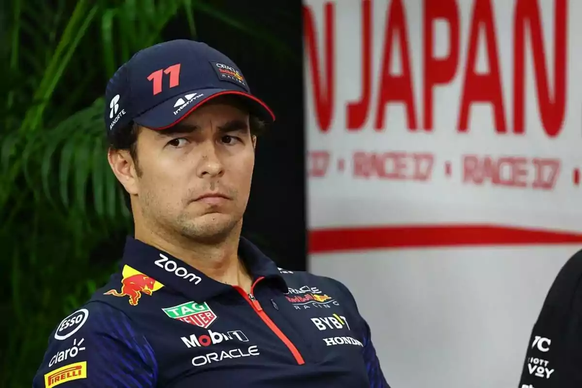 Piloto de Fórmula 1 con gorra azul y uniforme de Red Bull sentado frente a un cartel que dice Japan Piloto de Fórmula 1 con gorra azul y uniforme de Red Bull sentado frente a un cartel que dice Japan